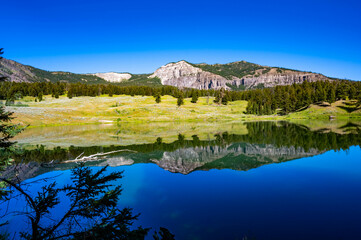 Yellowstone National Park's Trout Lake with beautiful reflections in the water and sun burst in the sky with mountains in the background