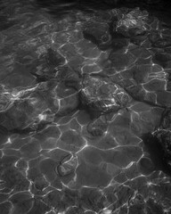 Black & white photo og clearly visible sea bottom of the mediterranean coast with turquoise water