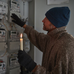 Checking the electricity power meter with a candle in cold winter days while there is power outage.