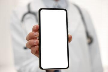 Doctor showing smartphone with blank screen in hospital, selective focus