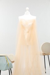 Mannequin with fabric and boxes on side tables against light grey background. Creating new outfit