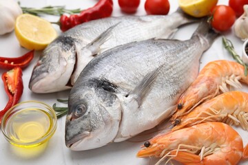 Fresh raw sea food and products on white tiled table, closeup