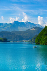 Obraz premium a small blue lake surrounded by high mountains with snowy peaks. travel and fishing concept
