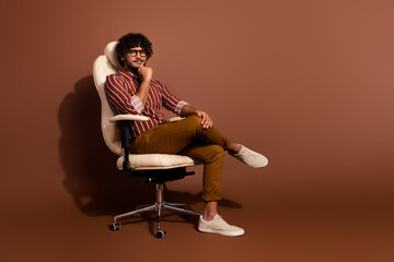 Full size photo of nice young man sit chair ponder wear shirt isolated on brown color background