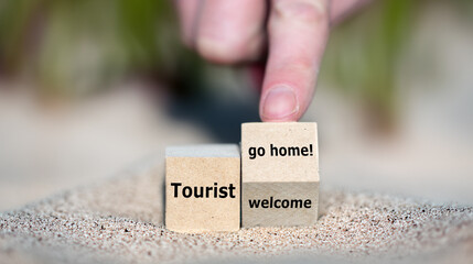 Hand turns cube and changes the expression 'tourist welcome' to 'tourist go home!'.