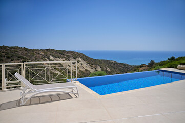 The white sun lounger was the scene's centrepiece, perfectly positioned beside the inviting pool. The summer landscape was idyllic, and the distant sea view added to the moment's tranquillity.