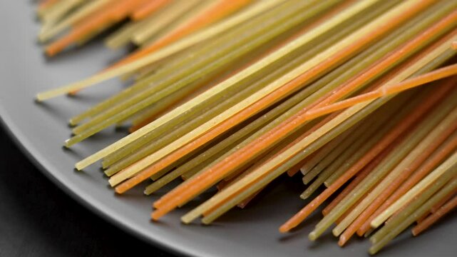 Artisanal Italian spaghetti pasta with a stunning array of uncooked strands showcasing a mix of colors and textures. Falling in slow motion. Close up