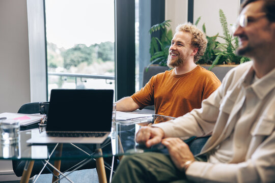 Happy male business colleagues engaging in a collaborative meeting with their team