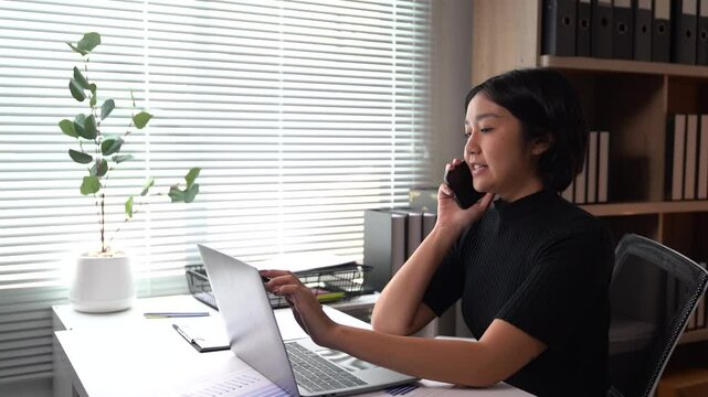 Asian businesses women working in the office used laptop and smartphone at her dest 