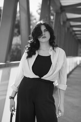 A girl in black trousers and a white shirt. Business lady in a black business suit against the background of a business center