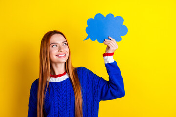 Photo portrait of pretty young girl hold look speech paper clouds wear trendy blue knitwear outfit isolated on yellow color background