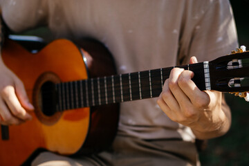Fototapeta premium young man is playing acoustic guitar outside on summer