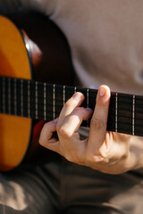 young man is playing acoustic guitar outside on summer