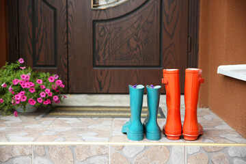 Two pairs of rubber boots on doorstep near entrance outdoors