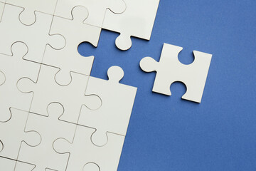 Fototapeta premium White puzzle pieces on blue background, top view