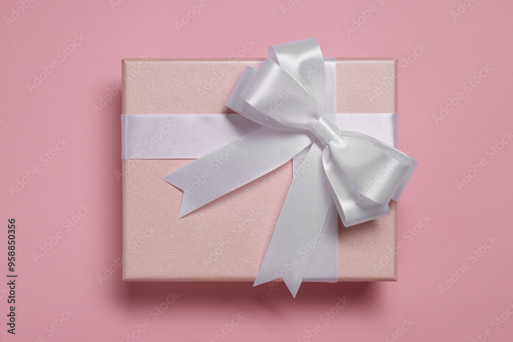 Sticker Gift box with bow on dusty pink background, top view