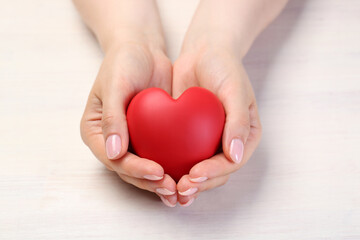 Woman with red decorative heart at white wooden table, closeup