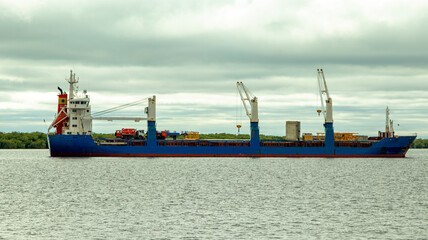 A large cargo sea vessel is at anchor, a dry cargo ship is at anchor
