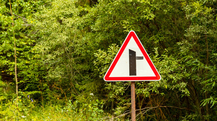 road signs warning of narrowing of the road, on a dirt road