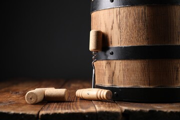 Corkscrew, corks and barrel on wooden table, closeup