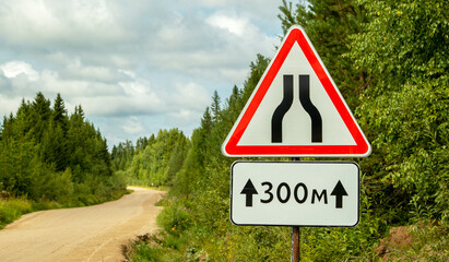 road signs warning of narrowing of the road, on a dirt road