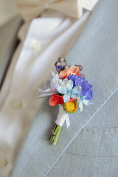 A colorful boutonni&egrave;re on a light suit jacket, perfect for weddings or formal occasions.

