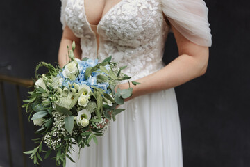 bride holding green bouquet of white and blue flowers