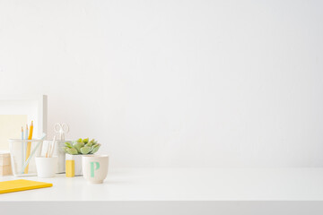 Creative desk with a blank picture frame or poster, desk objects, office supplies, books, and plant on a dark blue background.	