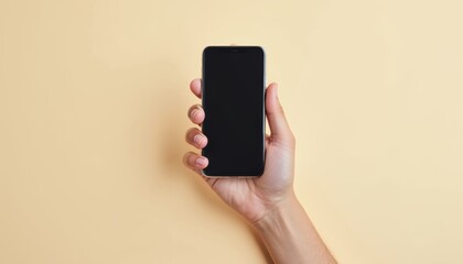 Hand holding a modern smartphone with a black screen against a beige background.