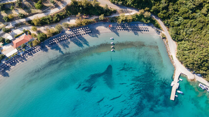 Aerial view of umbrellas, palms on the sandy beach of Indian Ocean at sunset. Summer holiday in Zanzibar, Africa. Tropical landscape with palm trees, parasols, white sand, blue water, waves. Top view © Nenad