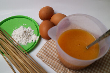 preparation for making egg rolls or telur gulung, using eggs mixed with flour and pepper. And pierced using a skewer.