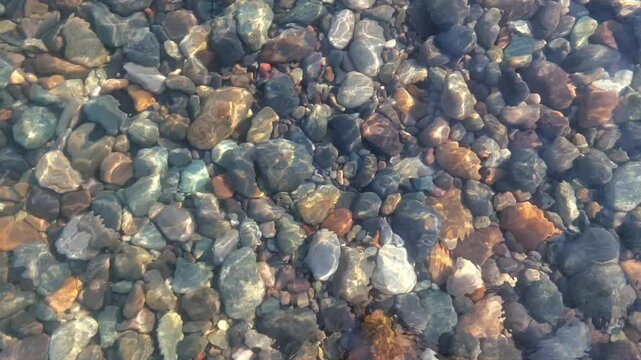 Multicolored pebble bottom of the Black Sea. Transparent water of the Black Sea. Clean sea and rocky bottom. Travel to Georgia. Vacation at sea in Batumi.