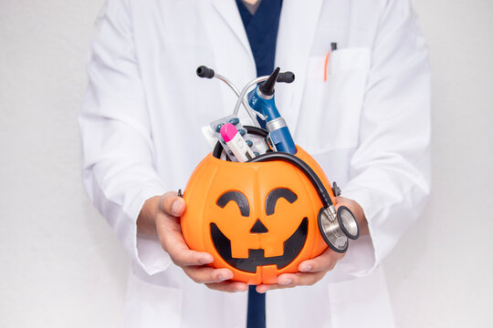 Unrecognizable doctor holding a toy Halloween pumpkin against
