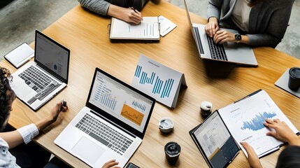 Team of four people reviewing data on laptops and documents.