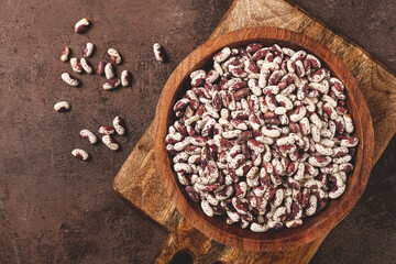 variegated beans, red with white spots, raw in a wooden bowl, top view, no people,