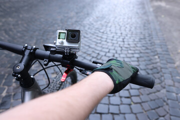 Obraz premium Man riding bicycle with modern action camera outdoors, closeup