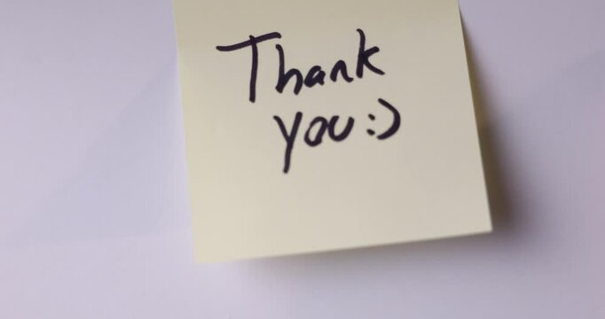 A person is sticking a note on a white wall. The note says I'm sorry.. video is in 24 fps