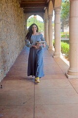 Woman Walking with Books in a Stone Corridor