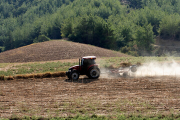 Fototapeta premium A tractor working in a field in early September to break up sunflower stubble from the previous harvest for winter wheat planting