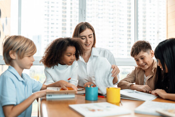 Teacher is teaching student about lesson from the books in the classroom, the children are happy. Some ask teacher, a boy in blue shirt is reading a book on his own and a girl is drawing. Erudition.