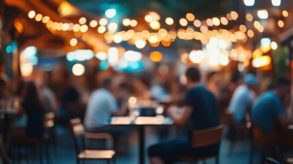 A vibrant outdoor dining scene with people enjoying food and drinks under string lights, creating a lively atmosphere.