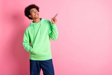 Photo of nice young man indicate finger empty space wear green hoodie isolated on pink color background