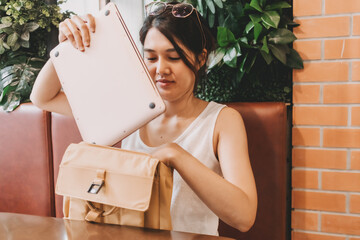 Asian woman putting her laptop computer into her backpack. Finished her work.