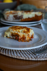 lasagna with tomato au gratin on a white plate at a table at home