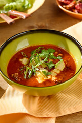 Vibrant Red Soup with Fresh Garnish in Bright Green Bowl on Light Wood Table - High Contrast Food Photography