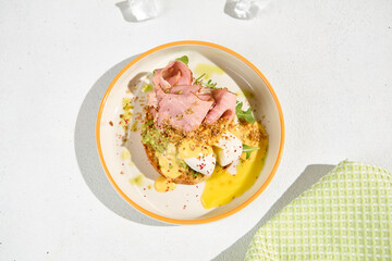 Brioche Bun with Ham, Poached Egg, and Hollandaise Sauce - Gourmet Breakfast Dish on White Background