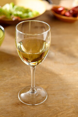 Elegant Glass of White Wine on Wooden Table with Warm Lighting and Soft Focus Background