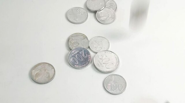 The scattered Rupiah coins symbolize the importance of financial planning and managing diverse resources for long-term economic stability and security.