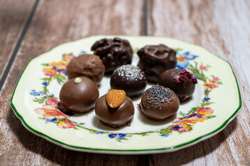 Assortment of fine chocolate bonbons on a plate on a wooden table.