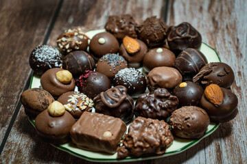 Assortment of fine chocolate bonbons on a plate on a wooden table.